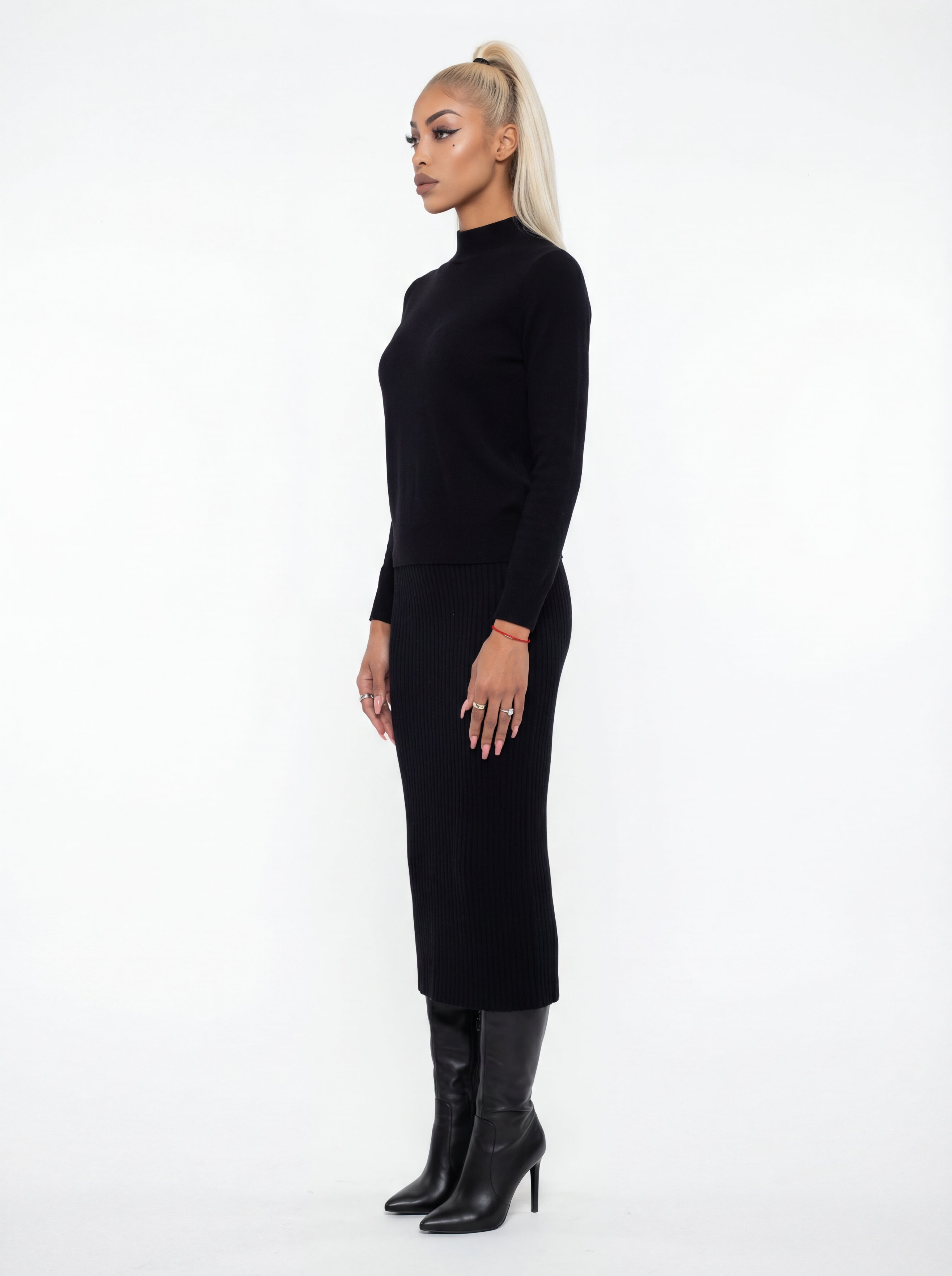 Woman wearing a black dress and black boots on a white background