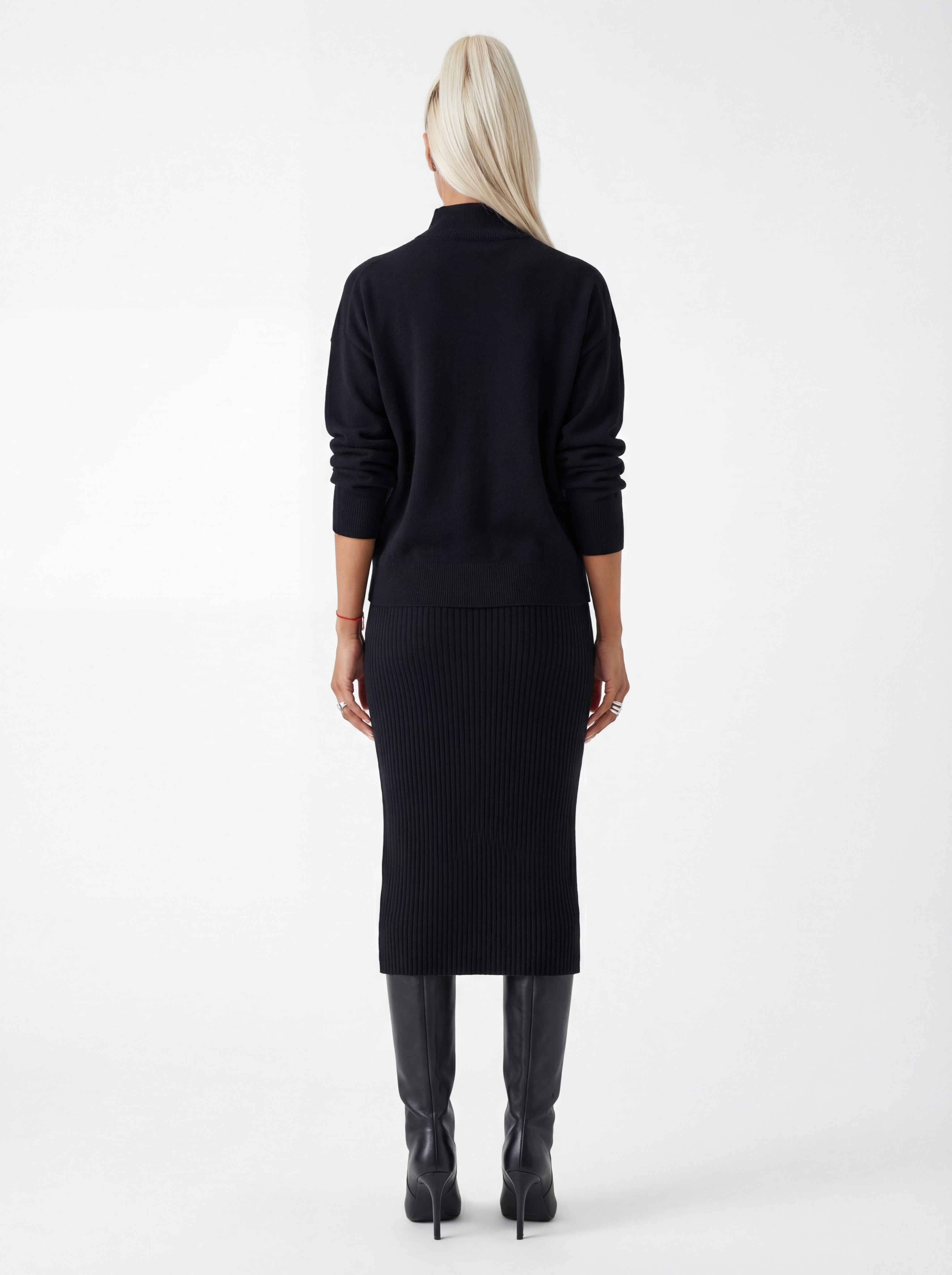Person wearing a black ribbed dress with long sleeves on a white background